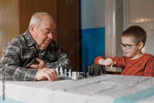 A grandfather and boy smile during chess. The concept shows family bonding and joyful learning.