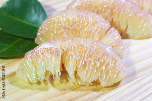 Close-up of Pomelo Flesh with Leaves on a Wooden Cutting Board