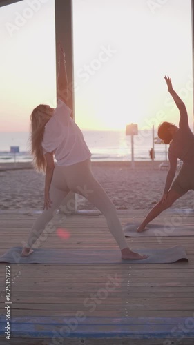 A serene beach sunset with two women and a man doing yoga