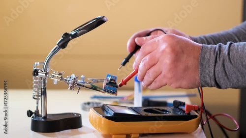 Close-up of hands soldering a printed circuit board with a soldering iron in a workshop. Concept of electronics repair, technology, DIY, and microchip maintenance.