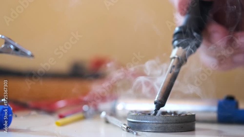 Close-up of hands soldering a printed circuit board with a soldering iron in a workshop. Concept of electronics repair, technology, DIY, and microchip maintenance.