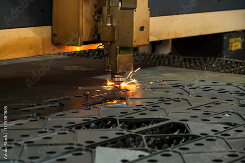 Automated industrial laser plasma machine is cutting metal sheet into pieces. Generates flying sparks as beam slices through, transforming material into metal polygons. Production of metal details.