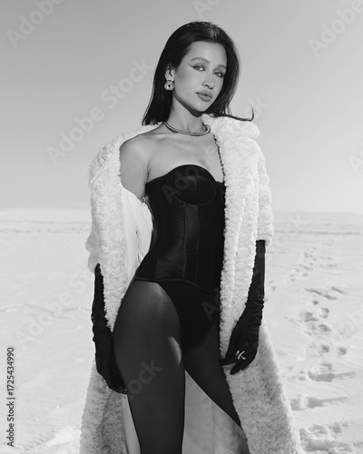 A beautiful and stylish girl in a fur coat walks on a sunny winter day on the frozen sea