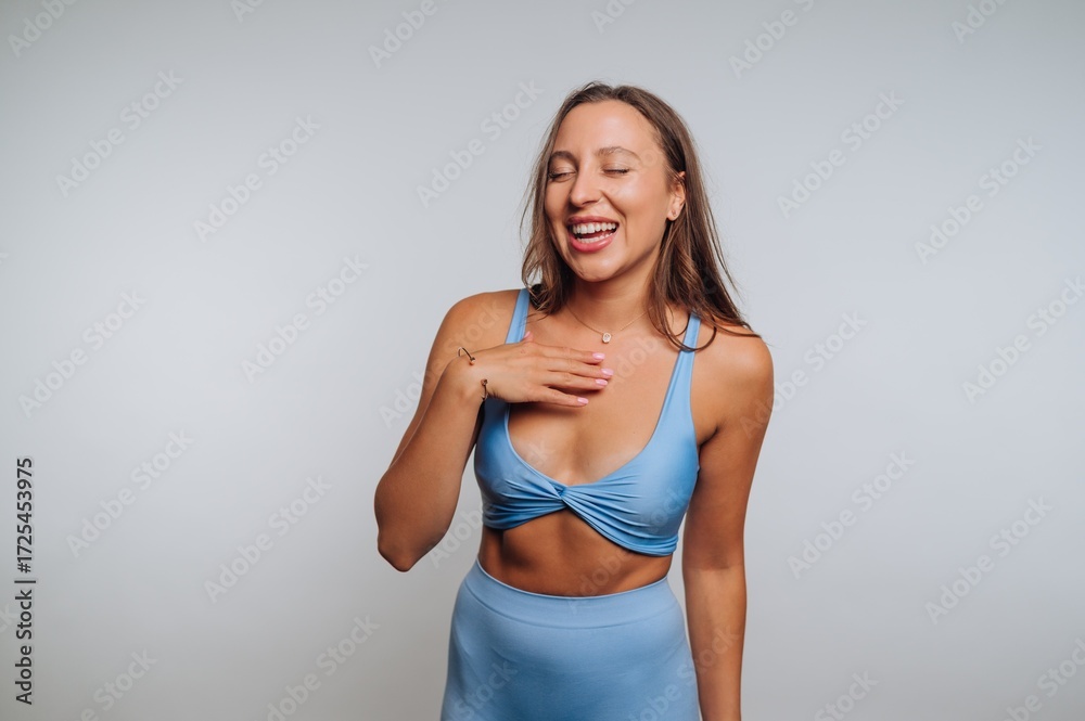 Fototapeta premium Woman in blue sportswear laughing with hand on chest.