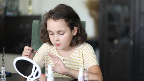 Cute little girl painting finger nails with polish. Kid doing manicure at home