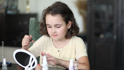 Cute little girl painting finger nails with polish. Kid doing manicure at home