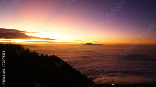 Valokuva Vibrant sunrise over a sea of clouds from a mountain peak, with distant peaks emerging from the mist and a colorful sky