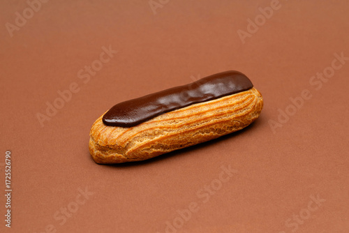 One french chocolate eclair on a brown background