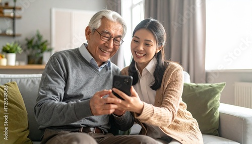 Young woman and her elderly father looking at a mobile phone together. Two generations using technology