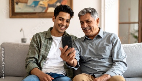 Young man and his elderly father looking at a mobile phone together. Two generations using technology
