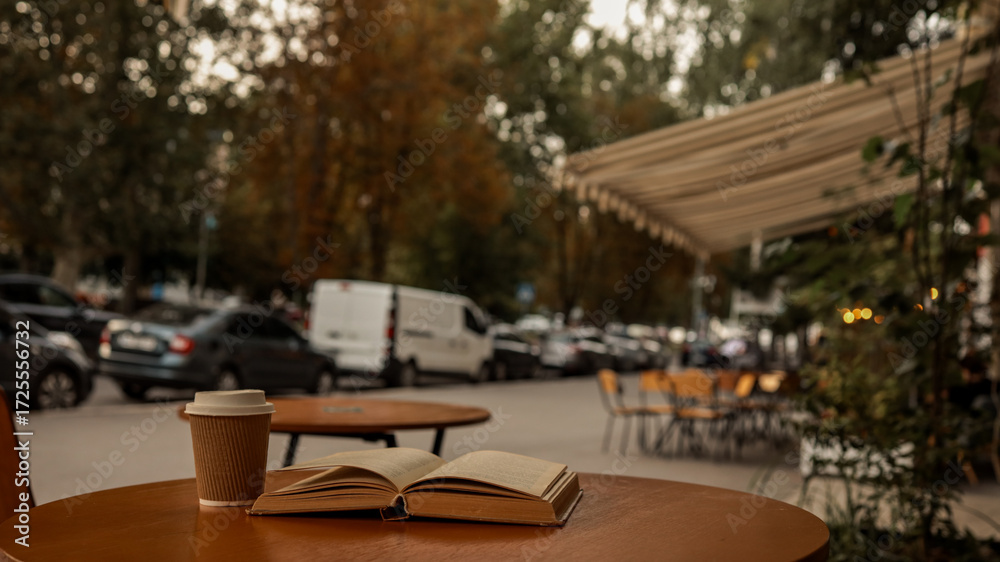 Fototapeta premium Coffee and a book on a table at an outdoor cafe