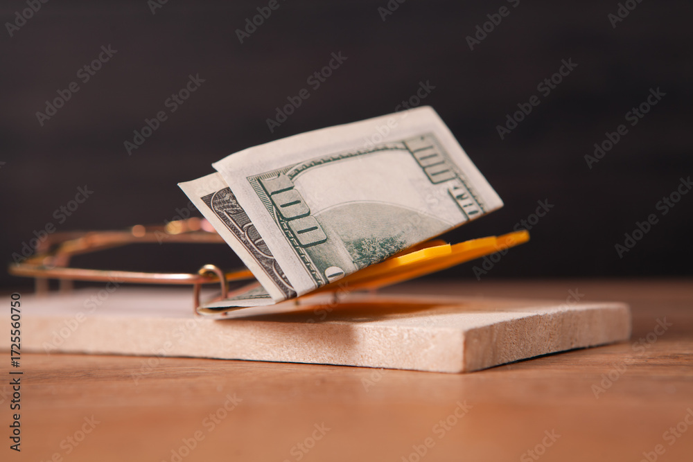 Naklejka premium Dollars in a mousetrap on a wooden background