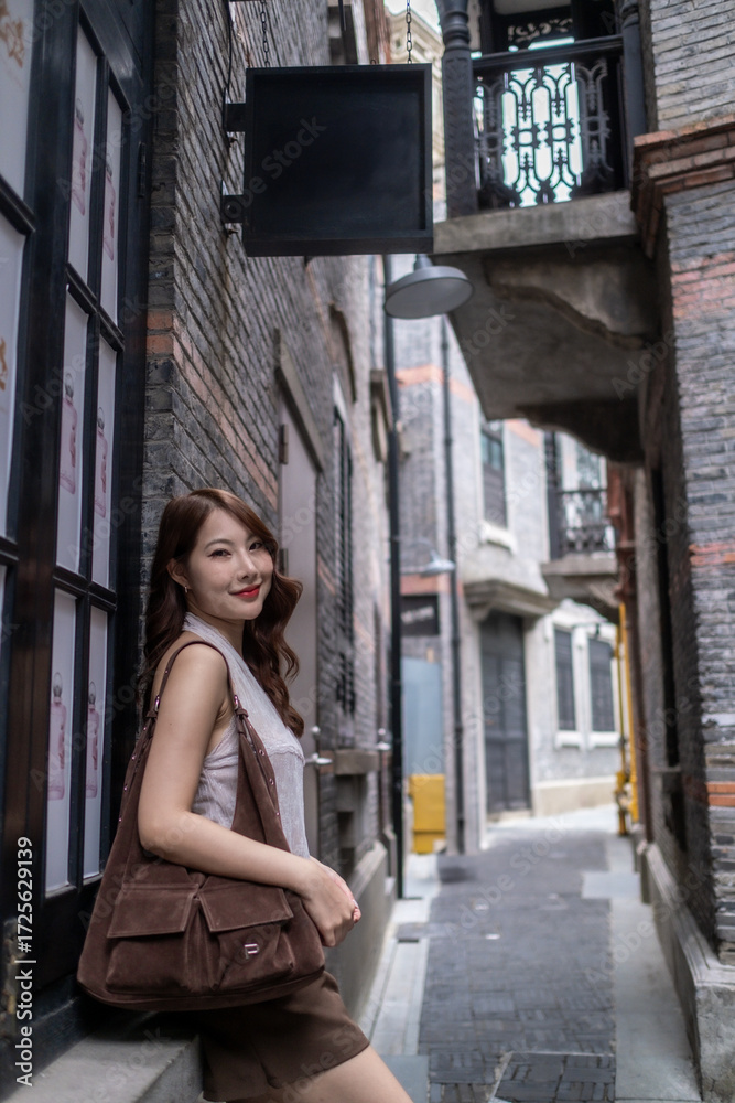 Fototapeta premium A woman is standing on a brick sidewalk in front of a building. travel concept.