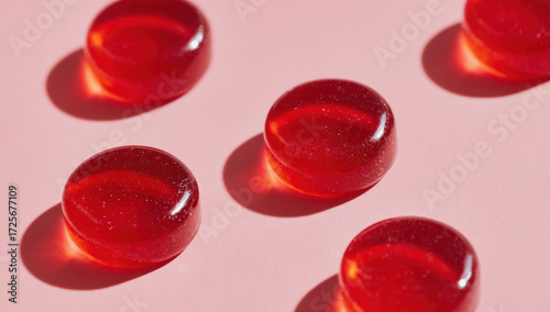 Colorful red gummy candies arranged on a pink background showcasing their shiny surface and oval shape