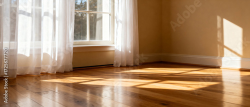 Bright and empty room with wooden floor and sheer curtains