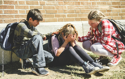 sad moment Elementary Age Bullying in Schoolyard. Childs consoling girl