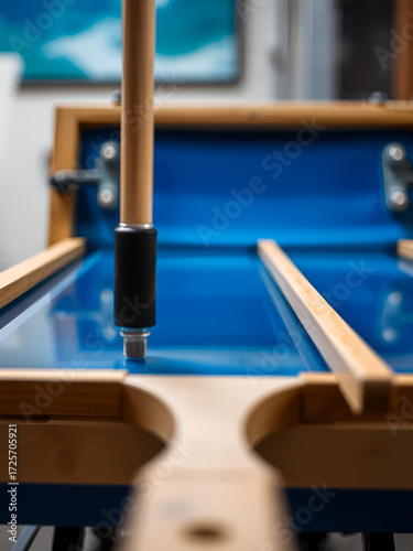 closeup on screen printing scene with blue color and wooden squegee standing at the end of a silkscreen between two print procedure - selective focus with narrow depth of field