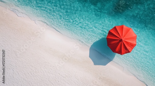 Bright Red Umbrella Stands Alone on Sandy Beach Beside Clear Blue Water on Su...