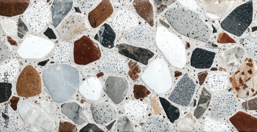A close-up showcases a terrazzo surface composed of various-sized, irregularly-shaped stone fragments embedded in a light-grey binder.  The stones display a palette of whites, greys, browns, and reds