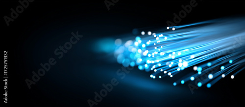Close up of fiber optic cables emitting a vibrant blue light on black background banner - high-speed internet and modern technology.