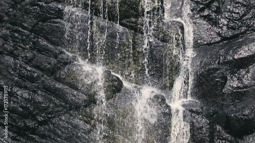 Beautiful waterfall streams flowing down the cliff in slow motion against the background of calm nature, an ideal abstract video for relaxation, spa, travel, advertising projects. Video at 120 fps.