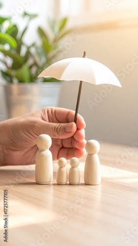 Hand holds umbrella over wooden family figures
