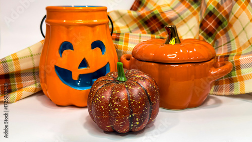 Halloween still life with pumpkin decor, ceramic jack o’lantern, soup bowl and plaid fabric