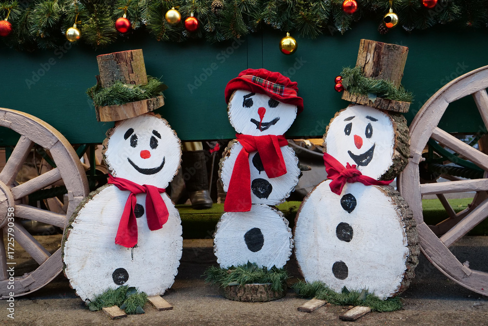 Fototapeta premium Three cheerful wooden snowmen are smiling