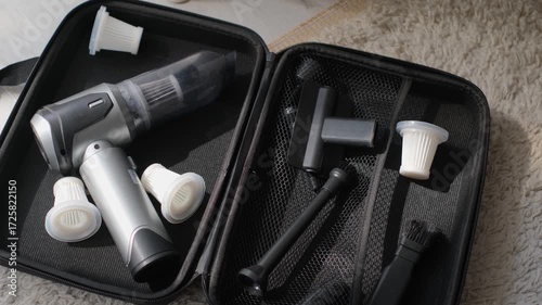 A close-up of a compact cordless vacuum cleaner and accessories in an open case