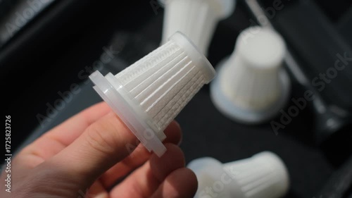 A man holds a small filter from a portable vacuum cleaner, close-up