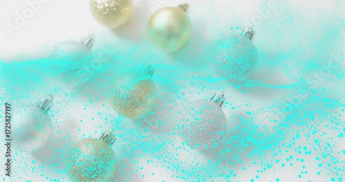 Teal particle cloud drifting right, sweeping baubles, then dispersing, revealing festive decoration