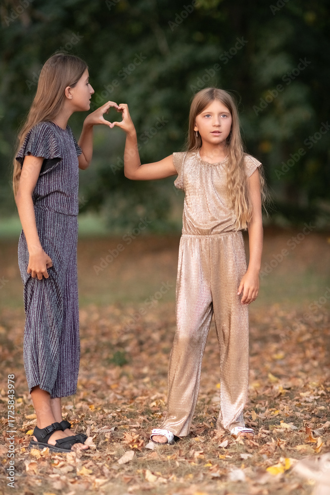 Fototapeta premium Portrait of two beautiful dressed children sisters outdoors.