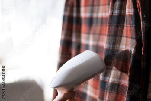 A woman steams a shirt, work at home using a steam iron.