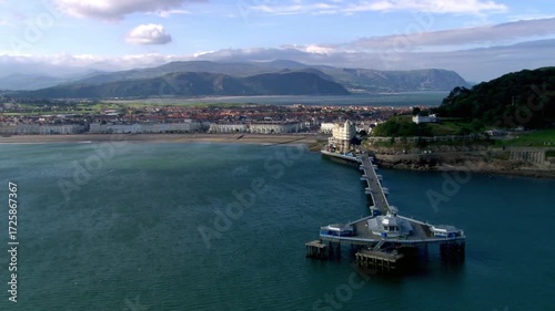Llandudno pier stretches out into the sea against a backdrop of mountains