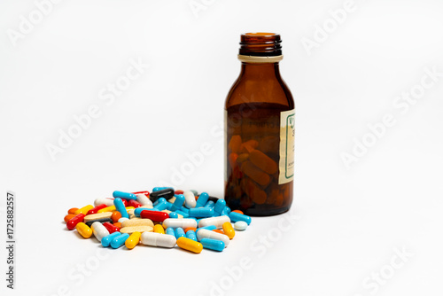 Different capsules, tablets and brown glass bottle on a white background. Pills of different colors are placed on a white background.