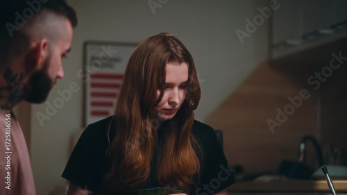 A cozy evening in a modern kitchen where a small group of friends gathers around a round table to play a board game