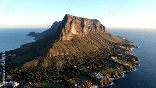 An aerial view captures the majestic table mountain rising above cape town, south africa, with the atlantic ocean stretching out to the horizon on a sunny day