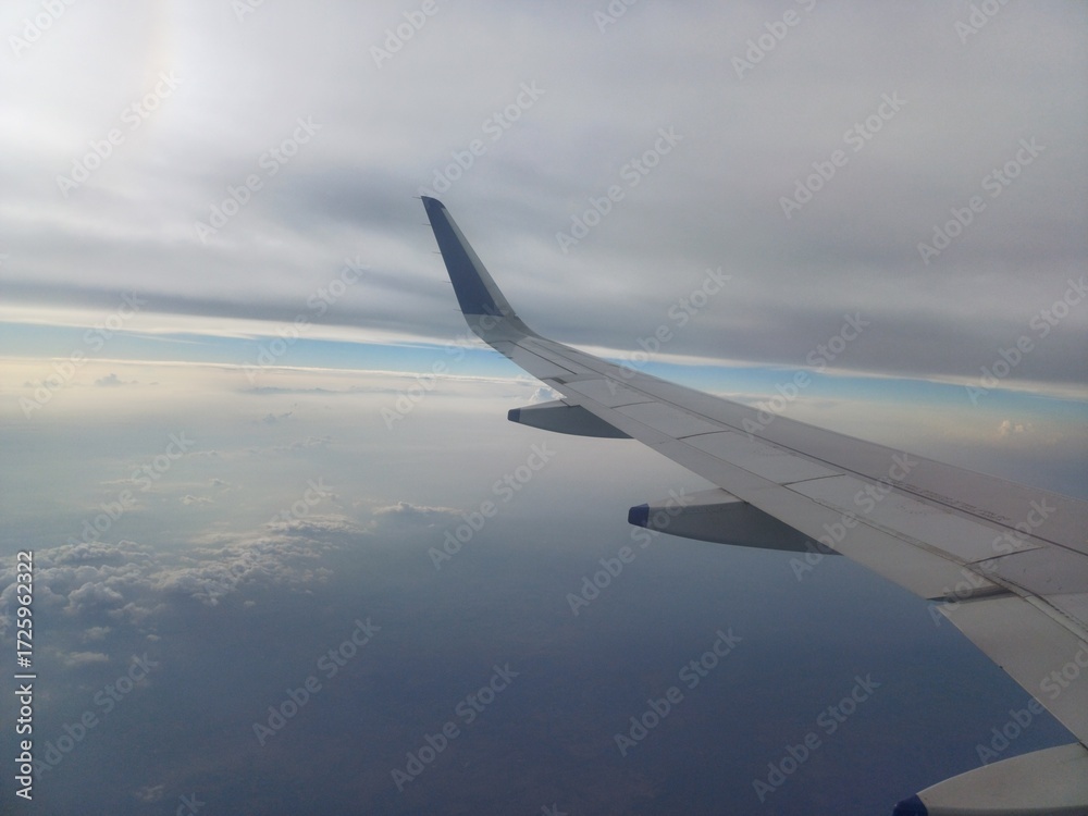 Fototapeta premium view from airplane window with cloudy sky, wing of airplane, view from the plane.
