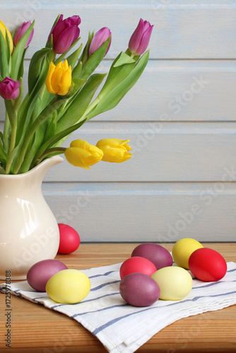 Fresh tulips in vase with colorful easter eggs in the cottage