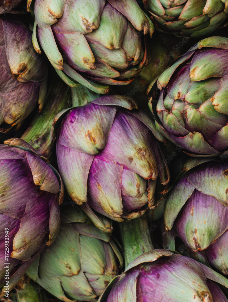 Obraz premium Fresh artichokes arranged beautifully showcasing their rich purple and green colors in a farmers market display during spring season