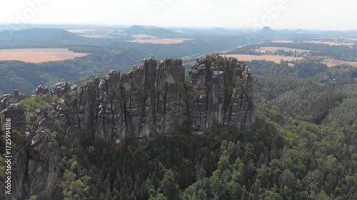 Dramatic rock formations rise above a lush forest in saxon switzerland, germany