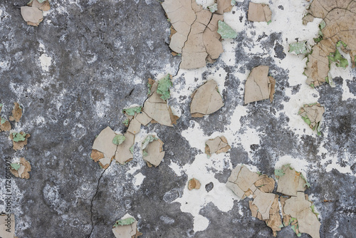 Peeling paint on the wall. Old concrete wall with cracked flaking paint. Weathered rough painted surface with patterns of cracks and peeling. Grunge texture for background and design. High resolution.