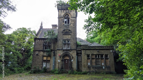 Abandoned stately home mansion estate. Eerie old derelict 'haunted house' in forest grounds. Creepy boarded up broken windows, stone pointed arches. Medieval country manor, gothic church tower ruins.