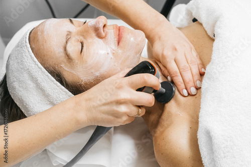 Bild auf Leinwand Woman receiving RF lifting treatment for facial rejuvenation, with a professiona