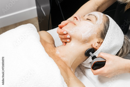 Tableau sur toile Woman receiving RF lifting treatment for facial rejuvenation, with a professiona