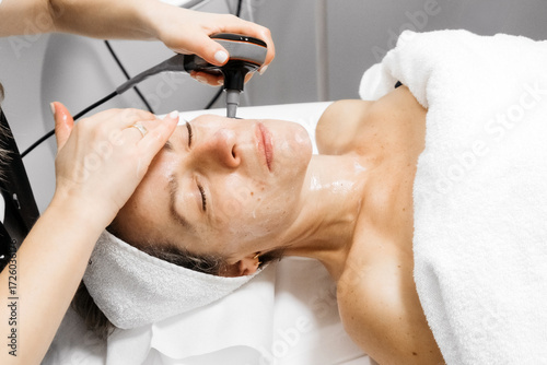 Foto Woman receiving RF lifting treatment for facial rejuvenation, with a professiona