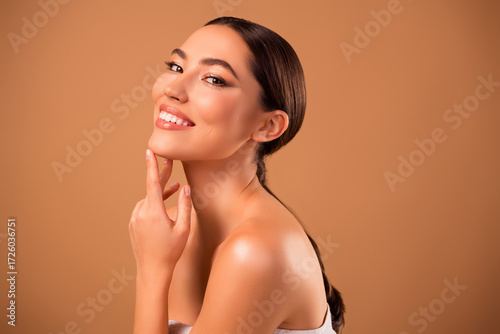 Smiling brunette woman showcasing beauty and skincare on a beige background representing luxury, style, and elegance