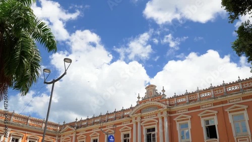 A beautiful orange building stands beneath a vibrant blue sky with fluffy clouds
