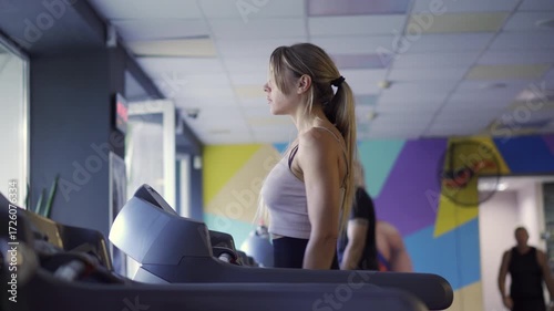 Cardio fitness: Focused female athlete using a modern automated treadmill for brisk walking