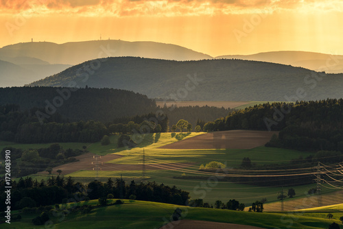 Golden sunset over rolling hills and lush fields in a serene countryside landscape